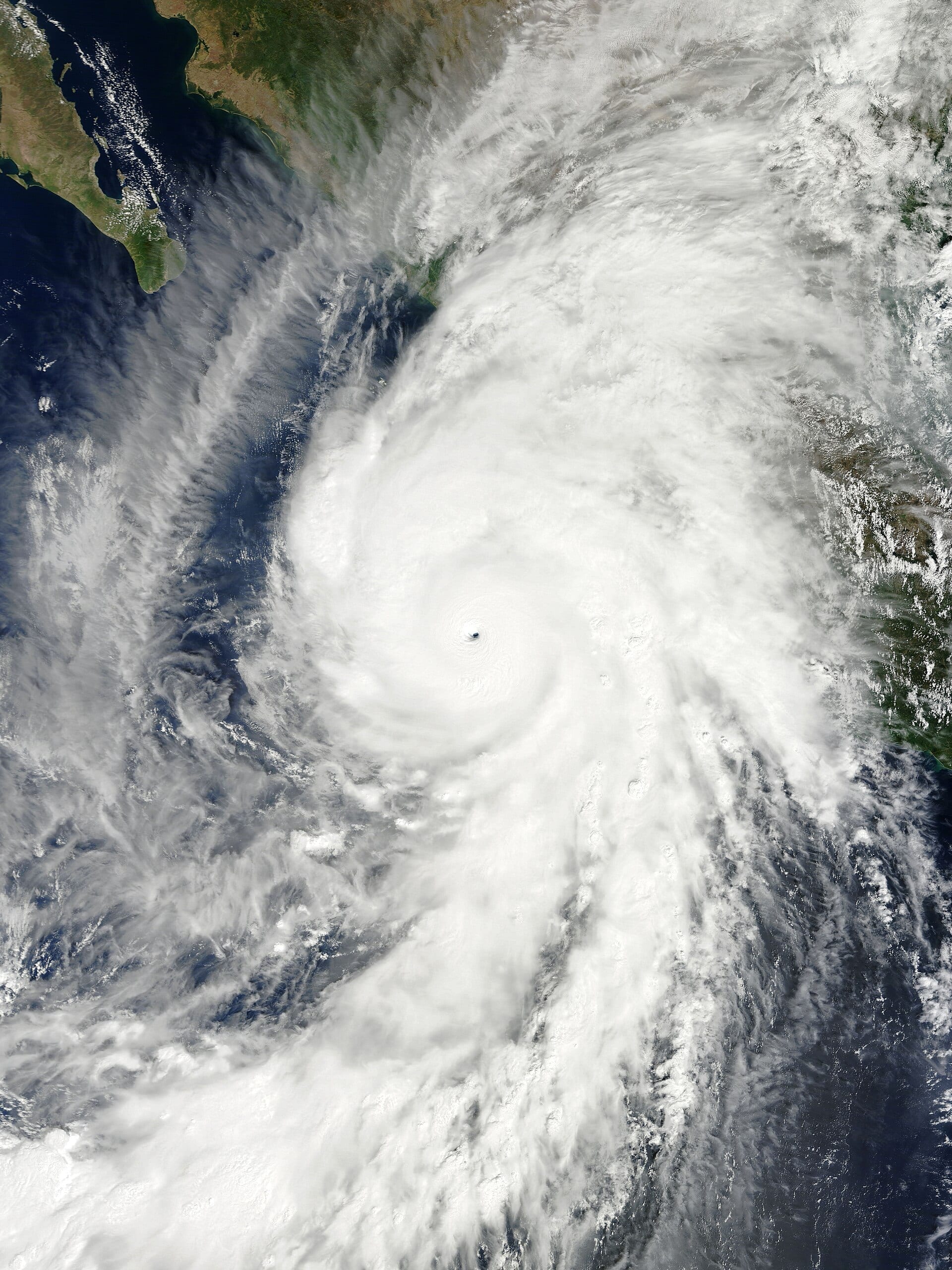 Vista satelital en color natural del ojo bien definido de un huracán mayor sobre el océano Pacífico, con la costa de México visible en la esquina superior izquierda.