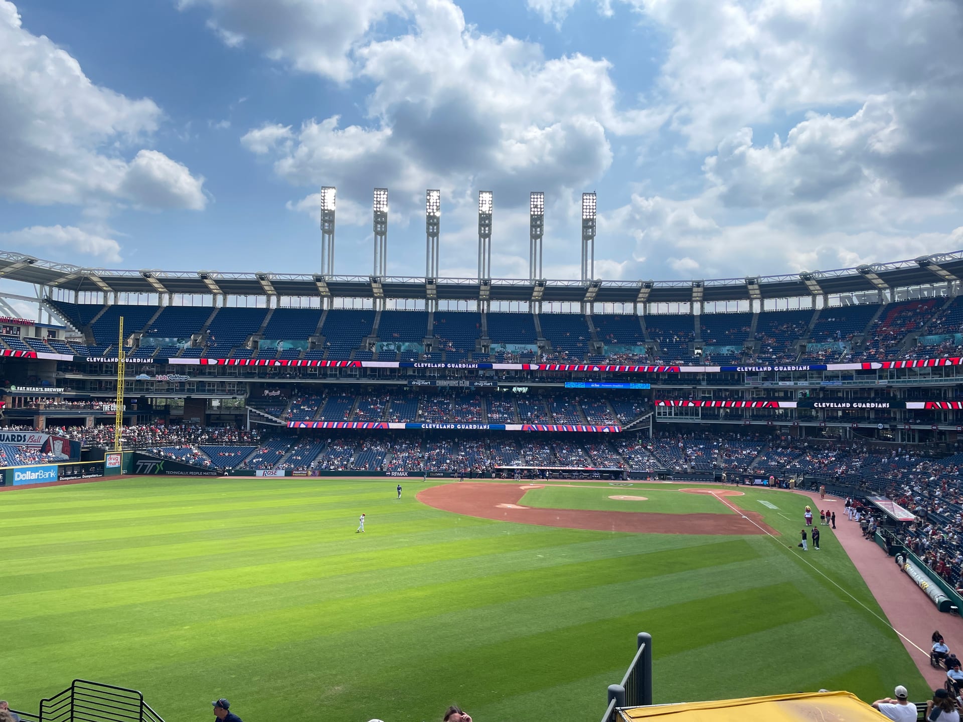 Panorámica del campo verde y las tribunas azules de Progressive Field bajo un cielo con nubes.