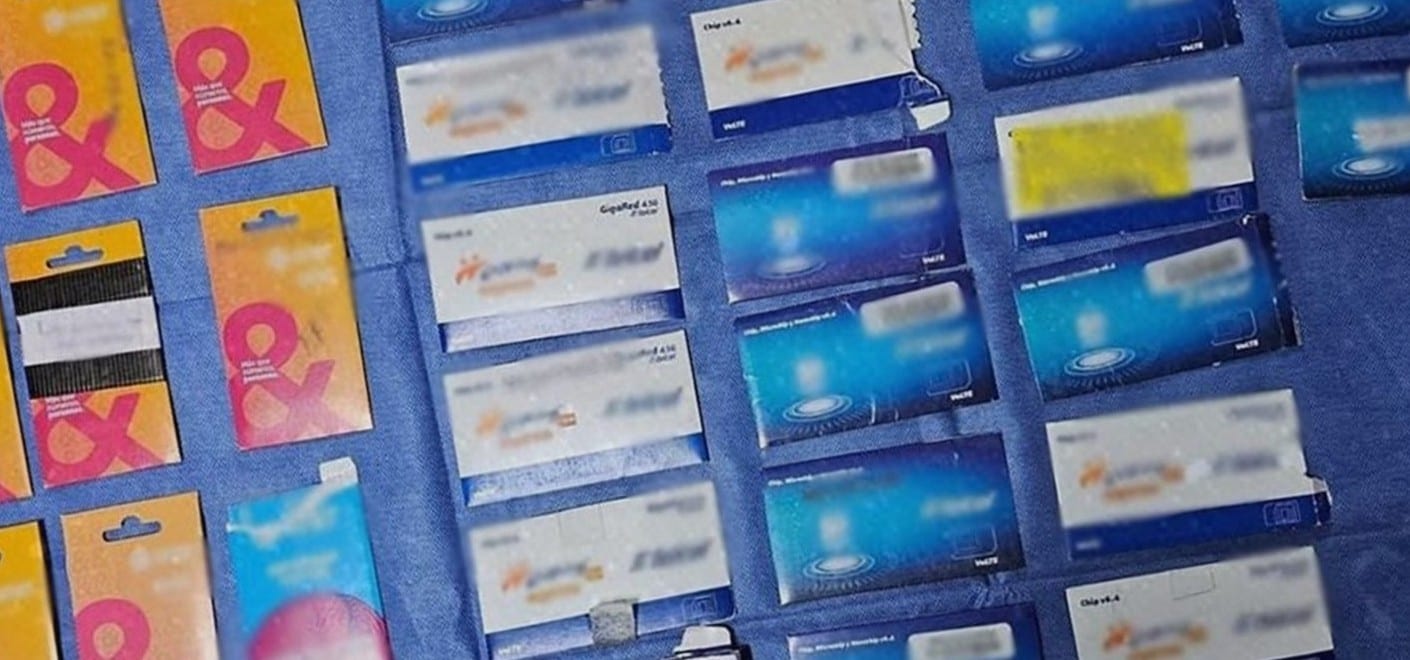 Decenas de tarjetas SIM y empaques de chips de varias compañías, ordenados sobre una tela azul.