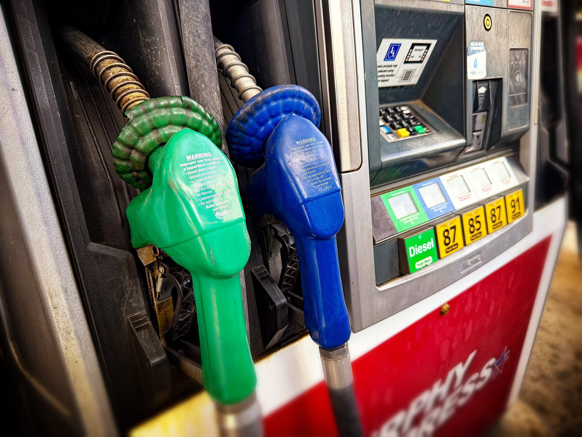 Dos pistolas de surtidor, una verde y una azul, junto a los botones de selección de combustible con la opción Diesel.