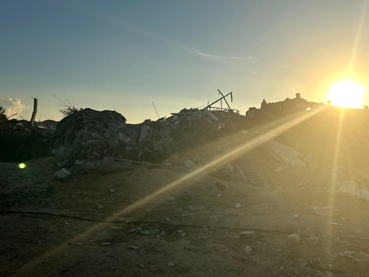 El sol se pone detrás de un montículo de escombros de un edificio derrumbado.