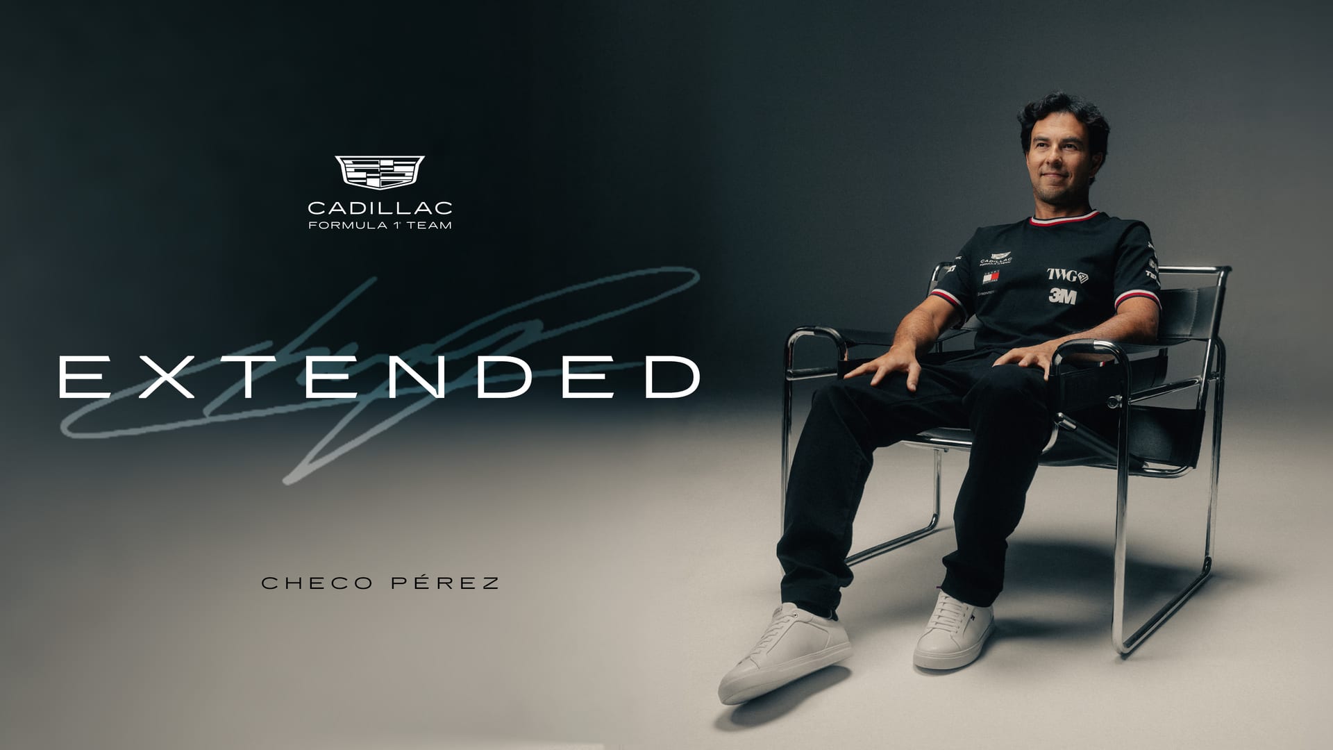 Sergio "Checo" Pérez in a black Cadillac team shirt sits in a chrome-tube chair against a gray backdrop, with the team logo and the word EXTENDED on the left.