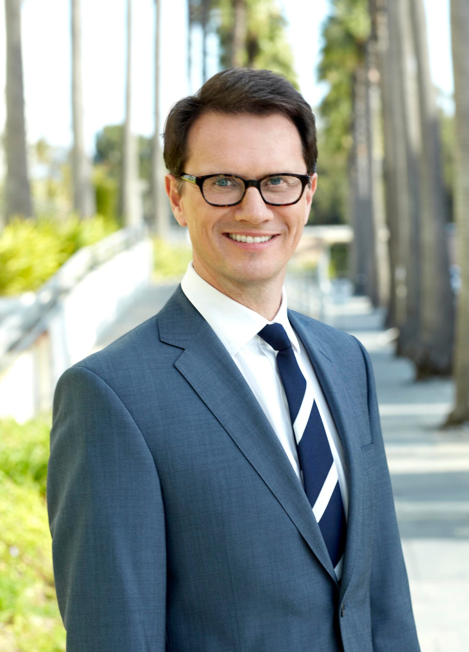 Retrato de Peter Rice, sonriente, con traje azul y lentes, en una fotografía de 2015.