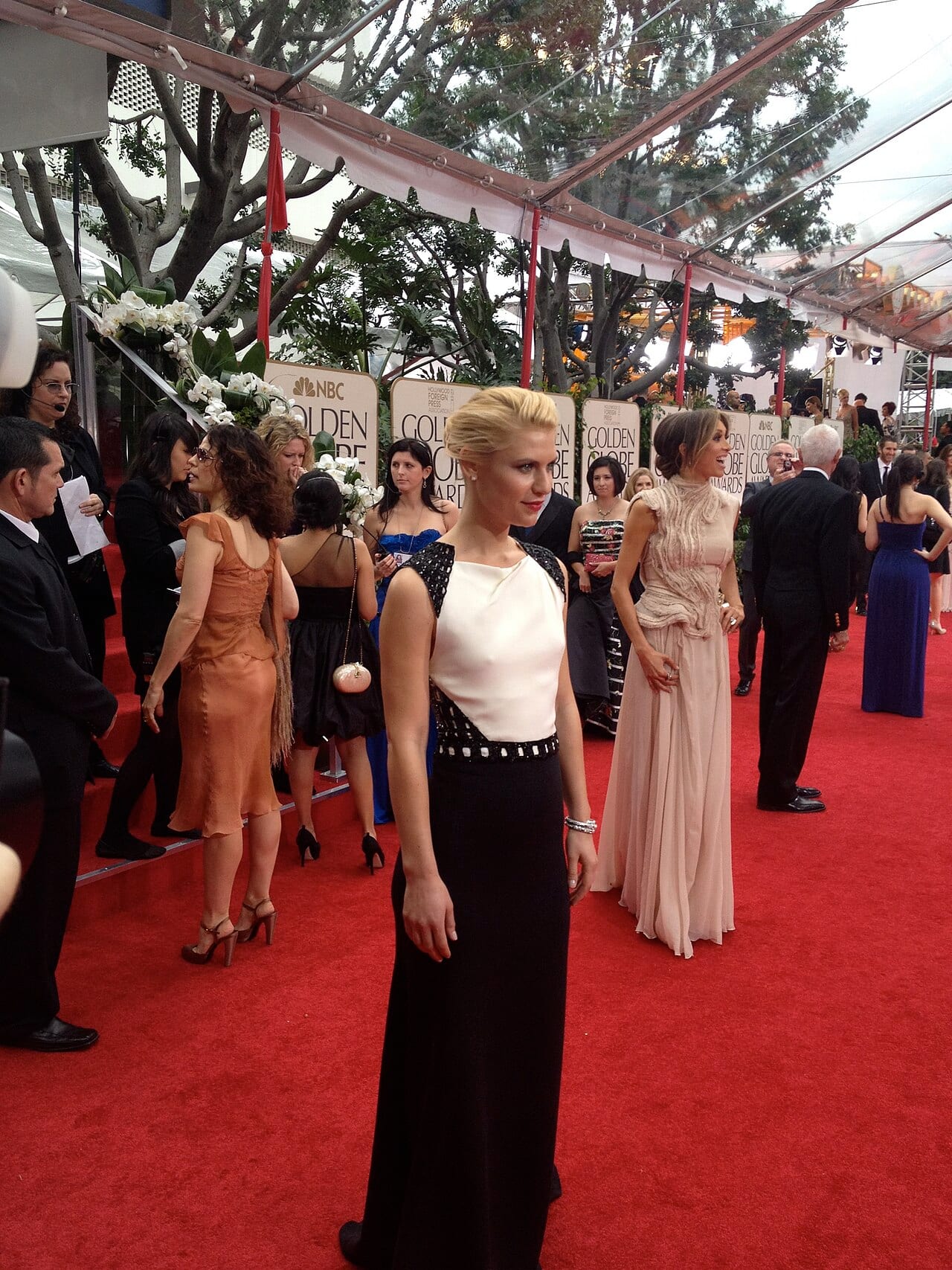 Claire Danes posa de perfil en una alfombra roja, con vestido largo bicolor y el cabello recogido.