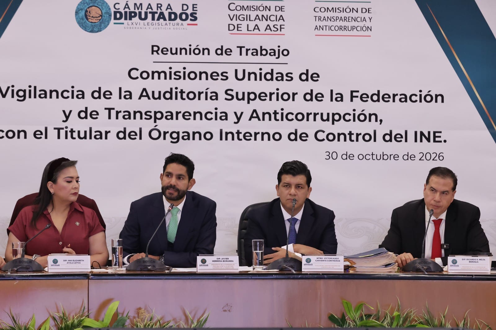 Cuatro integrantes del presídium sentados tras una mesa, frente a una manta de la reunión de trabajo de comisiones unidas del 30 de octubre de 2026.