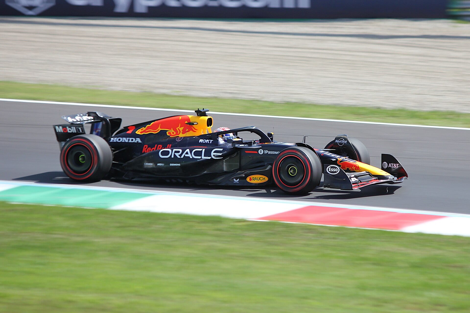 El Red Bull RB21 de Max Verstappen recorre la recta de un circuito con pianos verdes, blancos y rojos, en una imagen con efecto de movimiento.