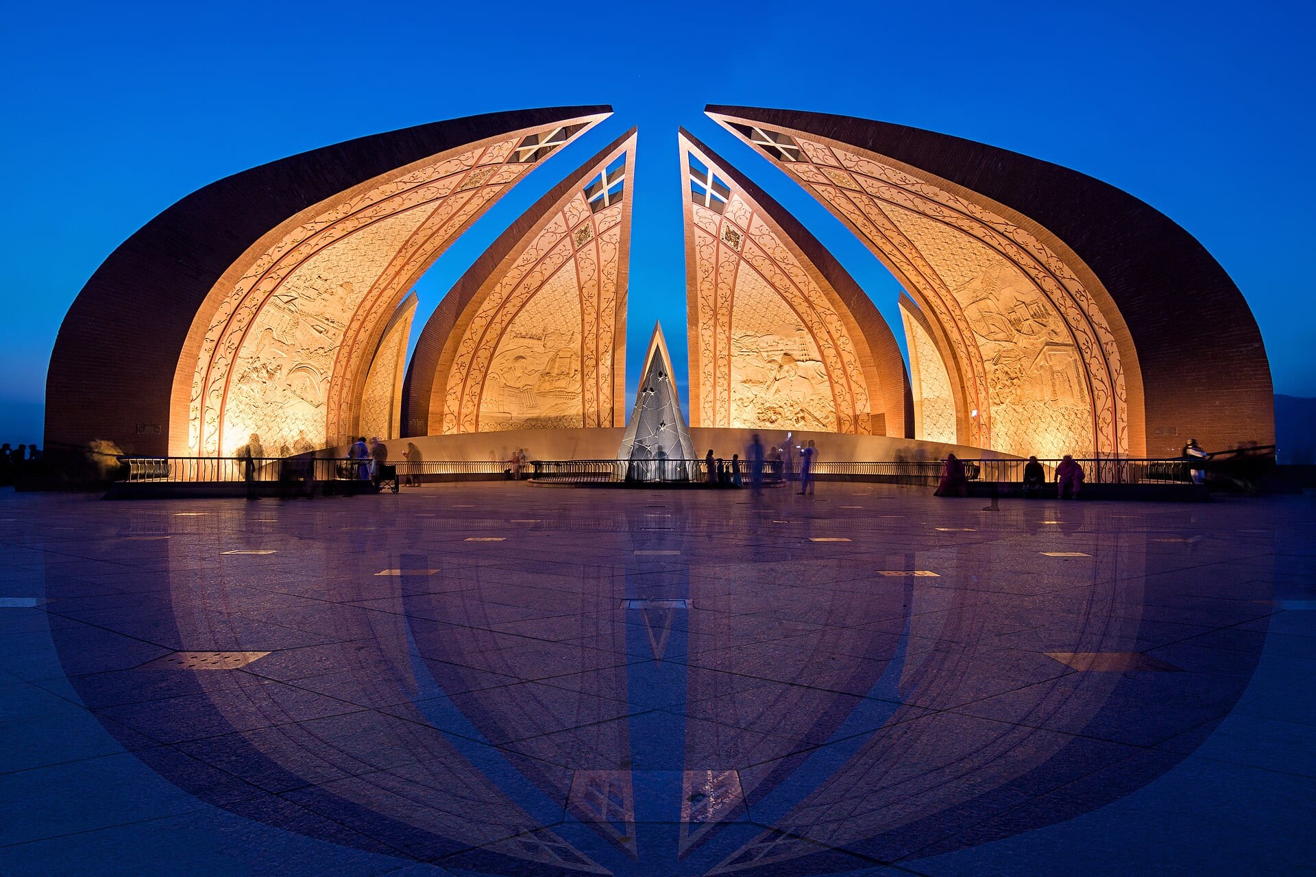 El Monumento de Pakistán, con sus cuatro pétalos de ladrillo iluminados, al anochecer y con su reflejo en la plaza de granito.