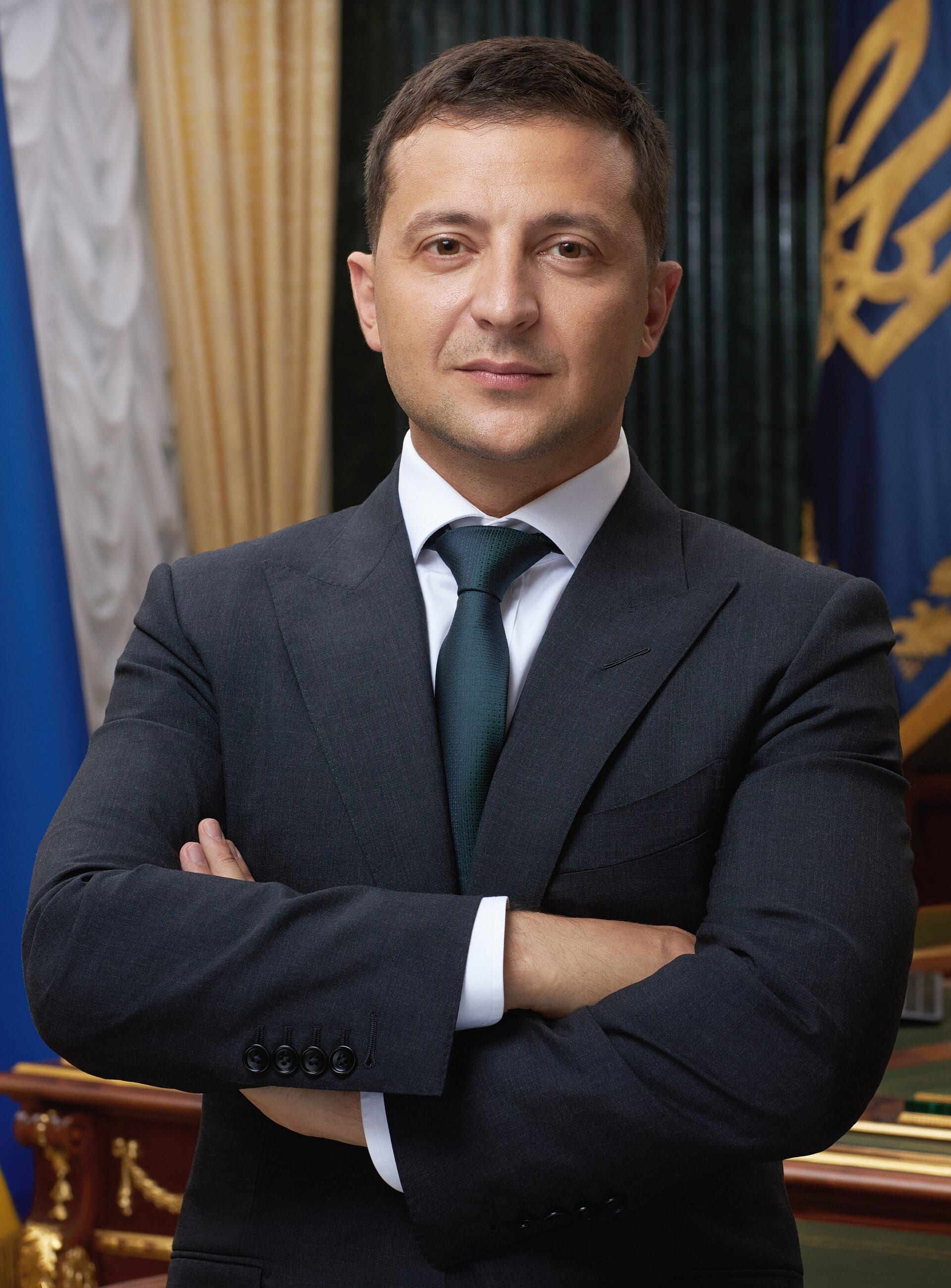 Retrato oficial del presidente ucraniano Volodímir Zelenski, de pie con los brazos cruzados.
