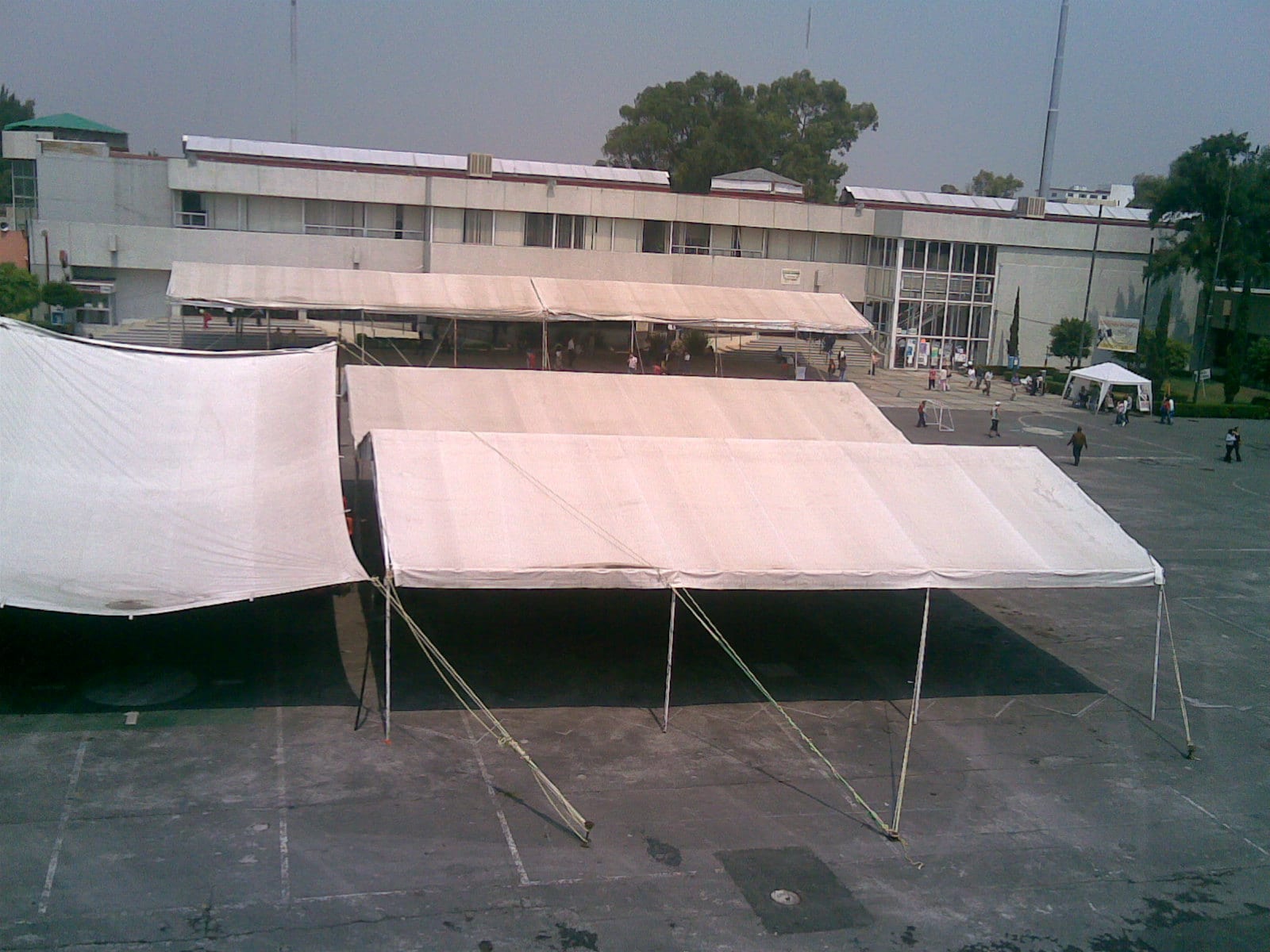 Carpas blancas montadas sobre una explanada de concreto frente a un edificio de dos pisos de la delegación Iztacalco.