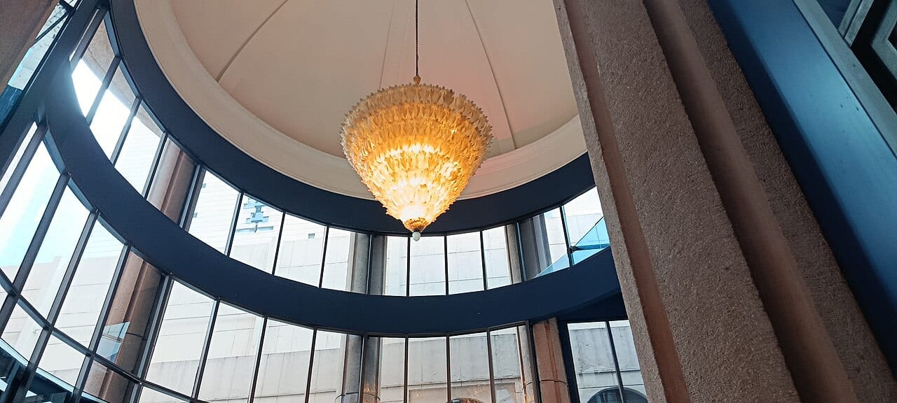Lámpara de cristal ámbar colgada bajo una cúpula, rodeada de ventanales curvos, en el vestíbulo del Hotel Marquis Reforma.