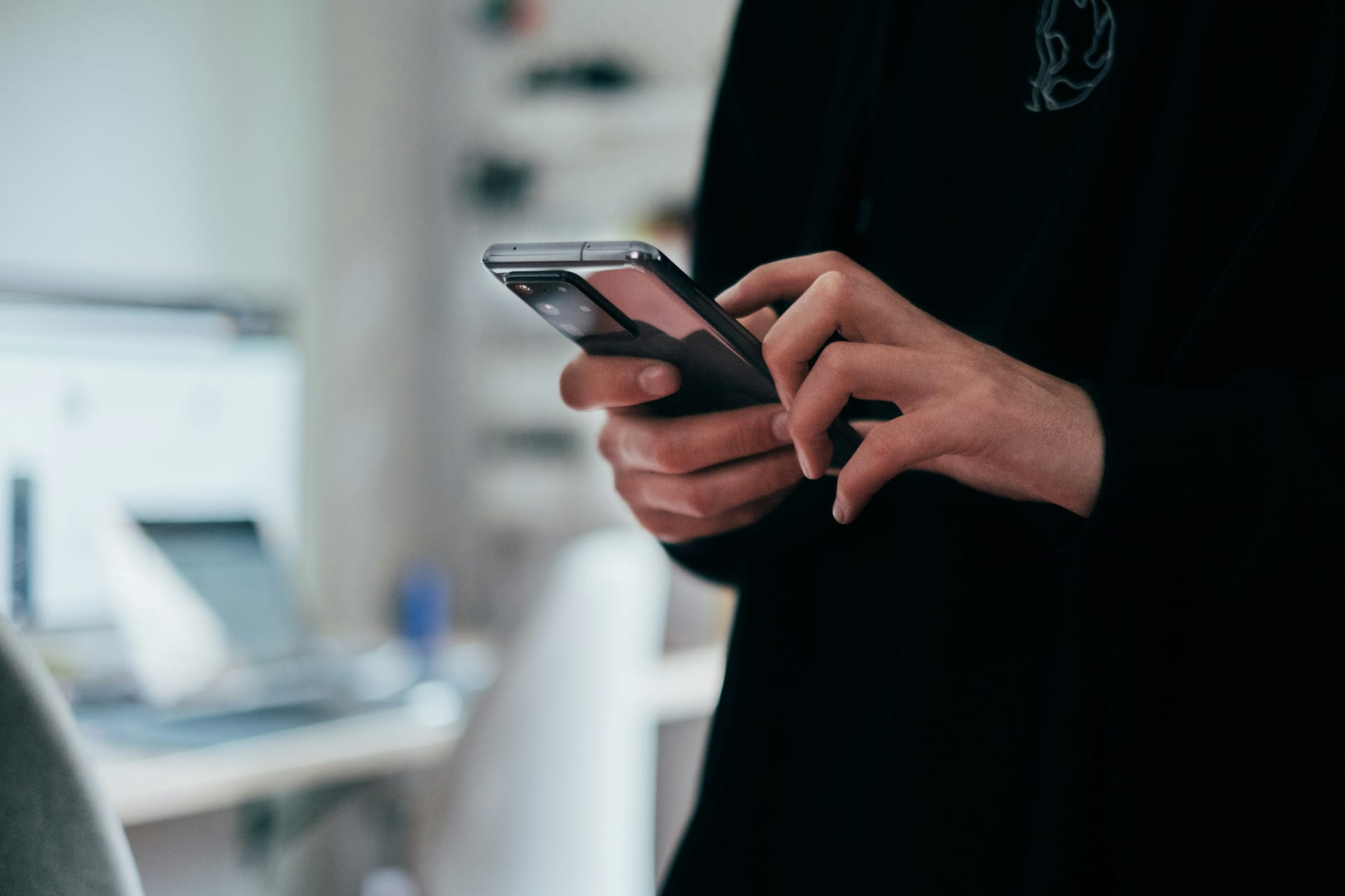 Una persona sostiene un teléfono inteligente Android con ambas manos y observa la pantalla.
