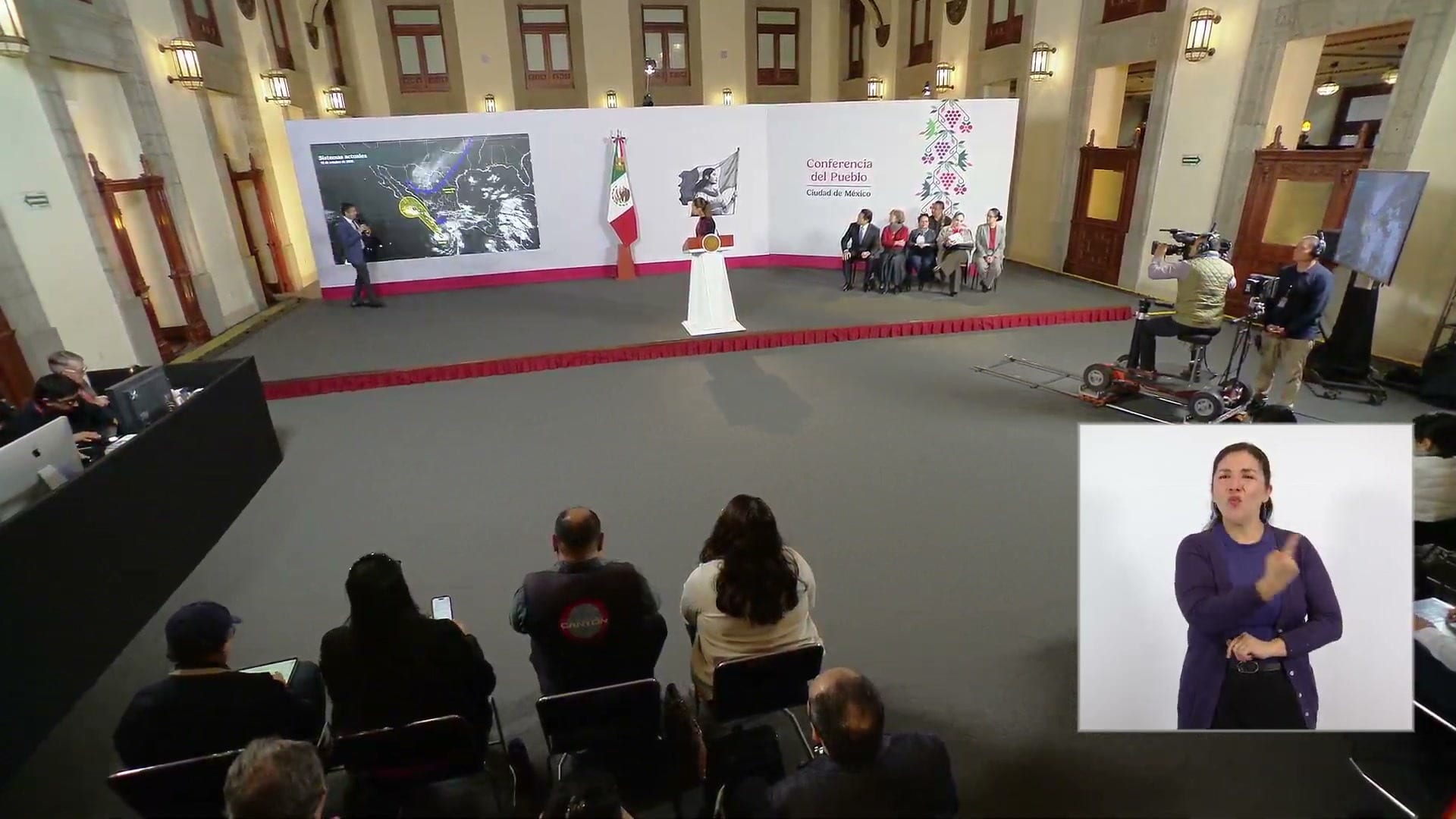 Un ponente señala un mapa del Pacífico mexicano con la trayectoria del ciclón, junto al podio de la conferencia matutina.