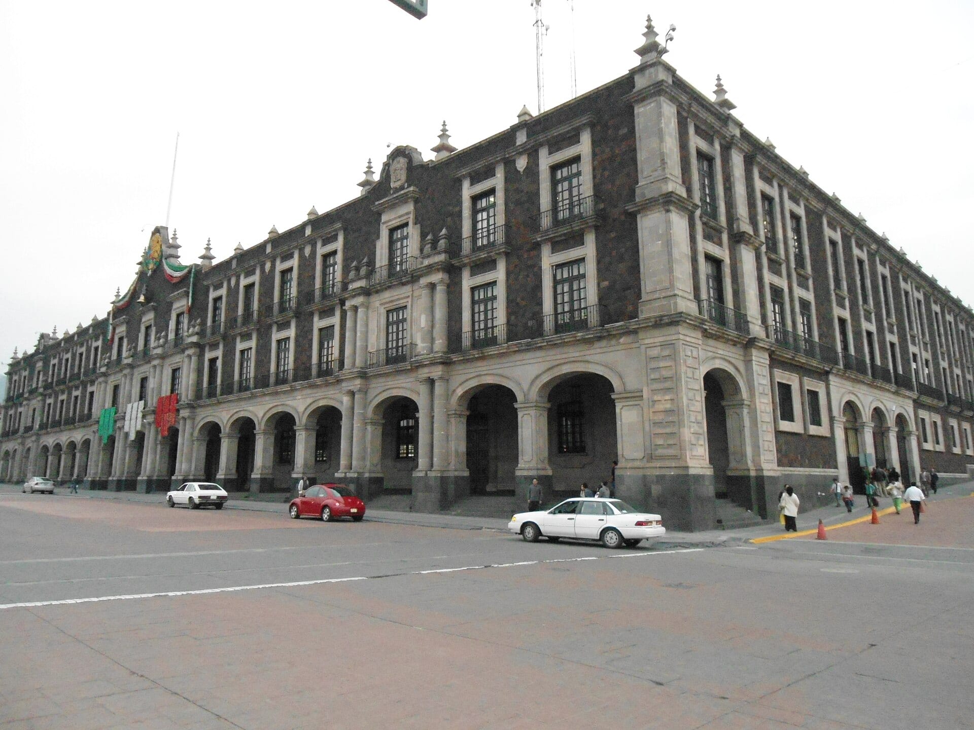 Esquina del Palacio de Gobierno de Toluca, un edificio de dos pisos con arcos de cantera y muros de roca oscura.
