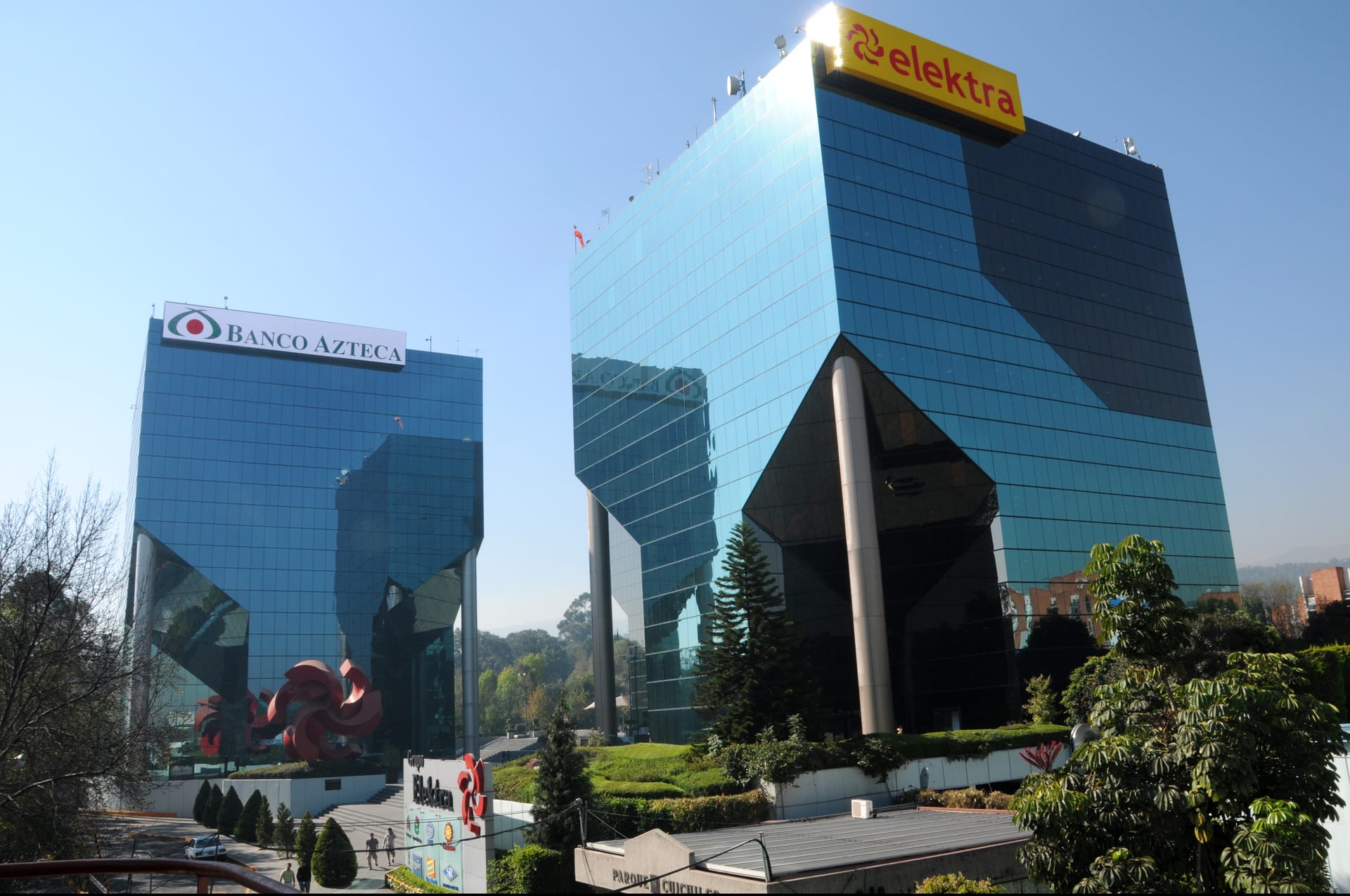 Las torres corporativas de Elektra y Banco Azteca, con sus letreros iluminados, vistas desde una calle de la Ciudad de México.