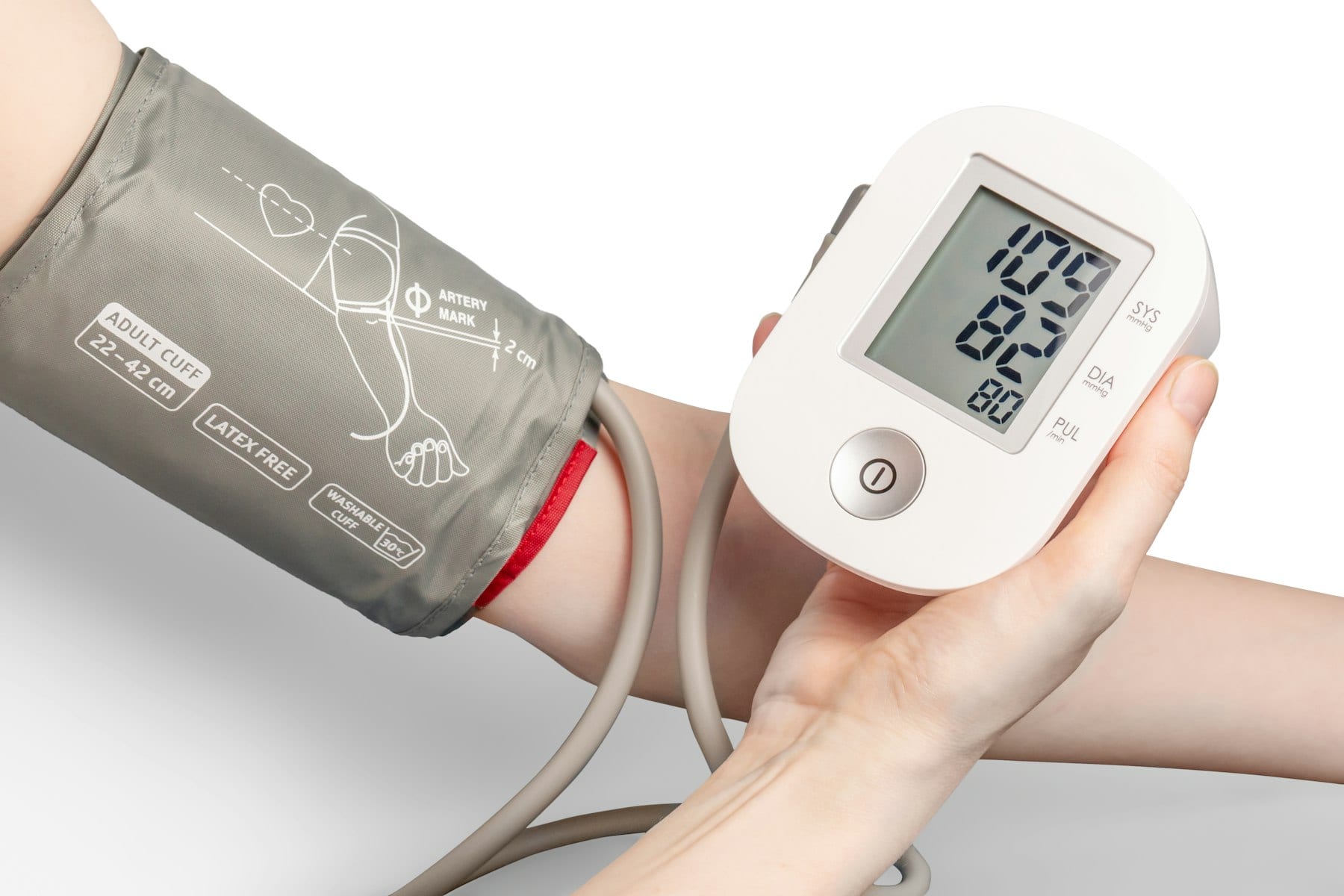 Una persona se mide la presión con un tensiómetro digital que lleva un brazalete gris colocado alrededor del brazo.