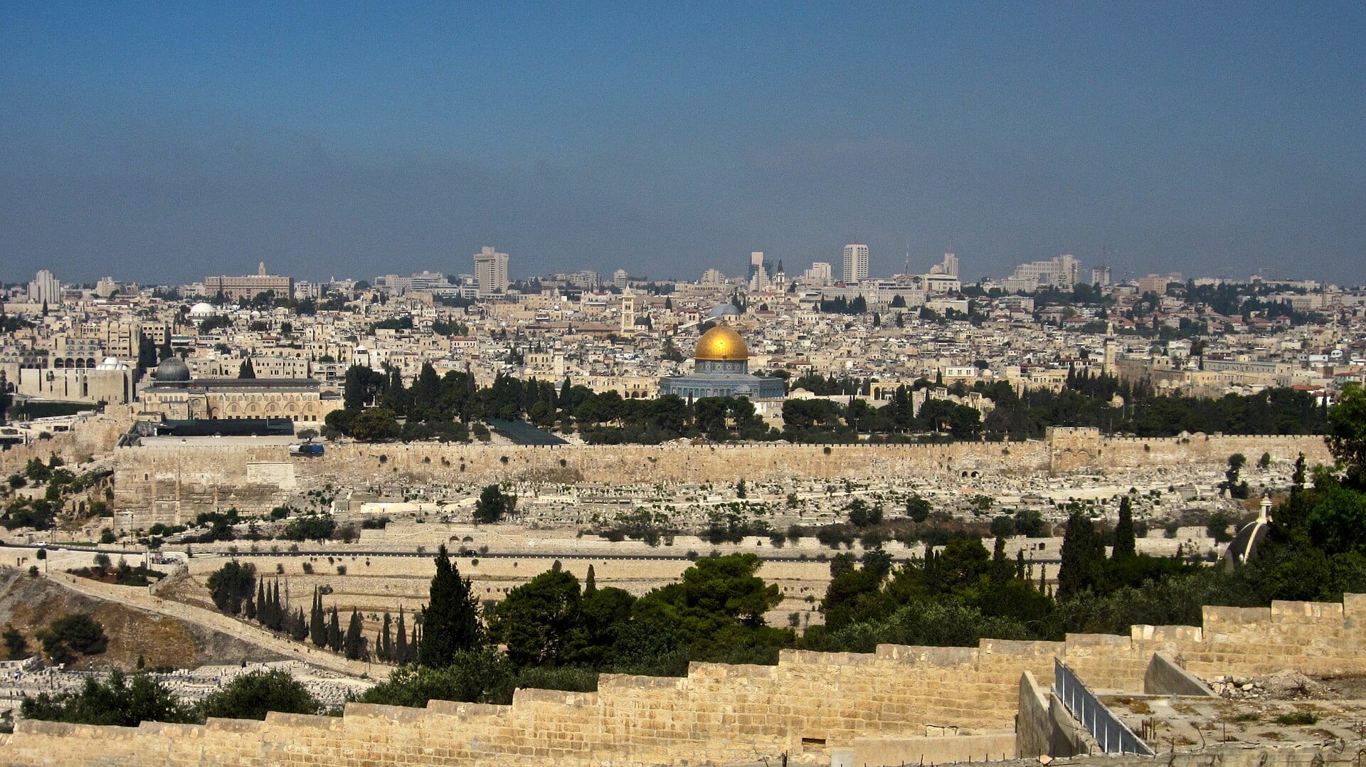 A view of Jerusalem's Old City from the Mount of Olives, with the golden Dome of the Rock at the center and the city wall in the foreground.