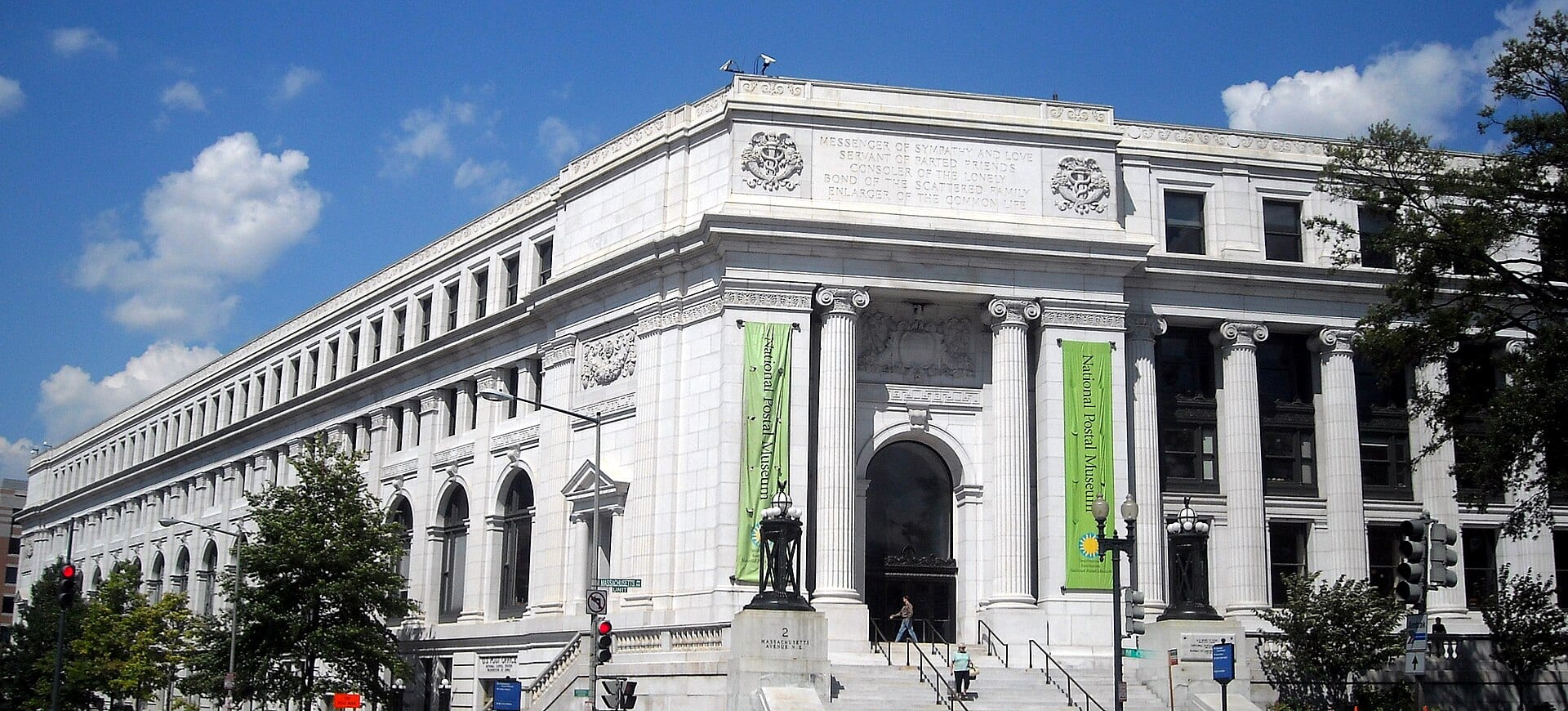 Fachada de mármol blanco con columnas del Postal Square Building, en Washington, bajo un cielo azul con nubes.