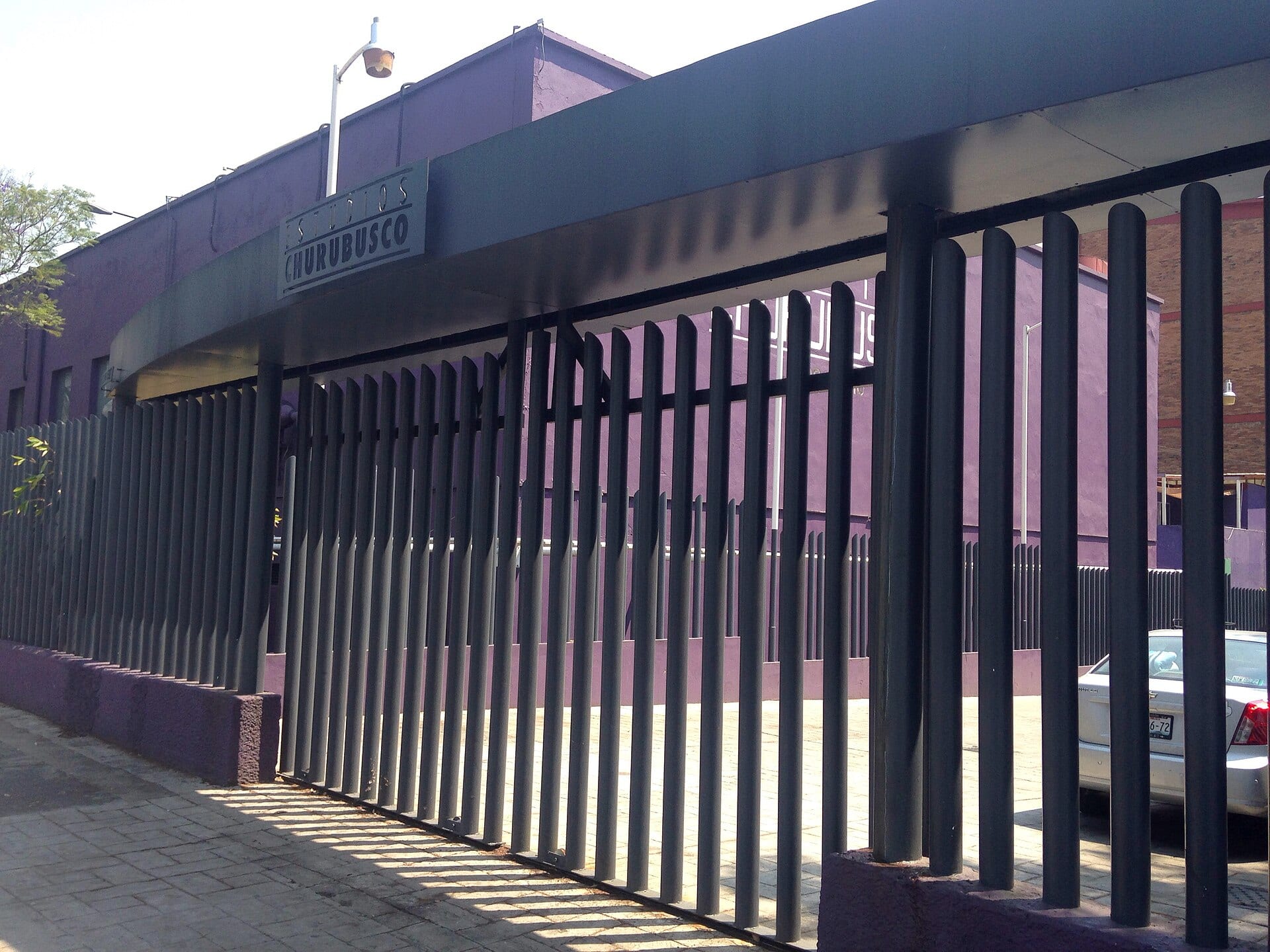 Entrada de los Estudios Churubusco vista desde la calle, con el acceso del complejo y árboles alrededor.