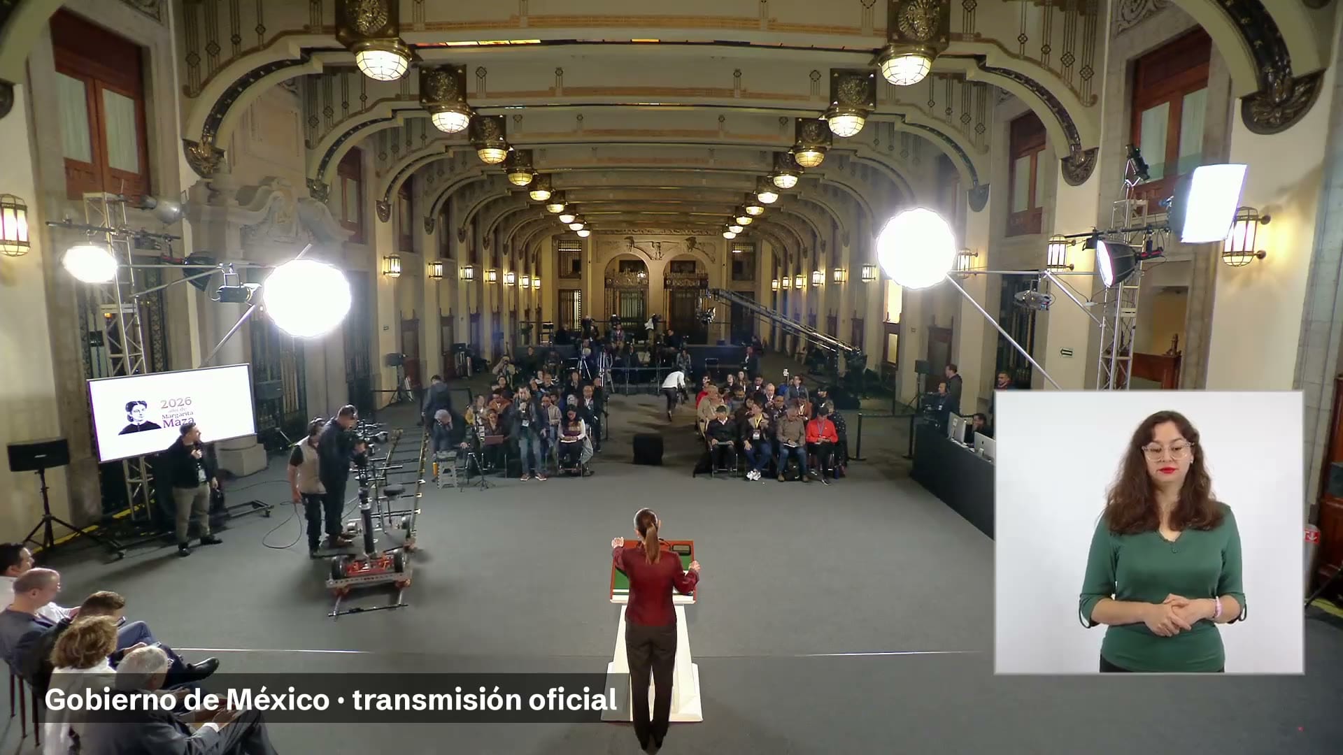 La presidenta, de espaldas, en el podio del salón de la conferencia matutina, con periodistas al fondo y una intérprete de lengua de señas a la derecha.